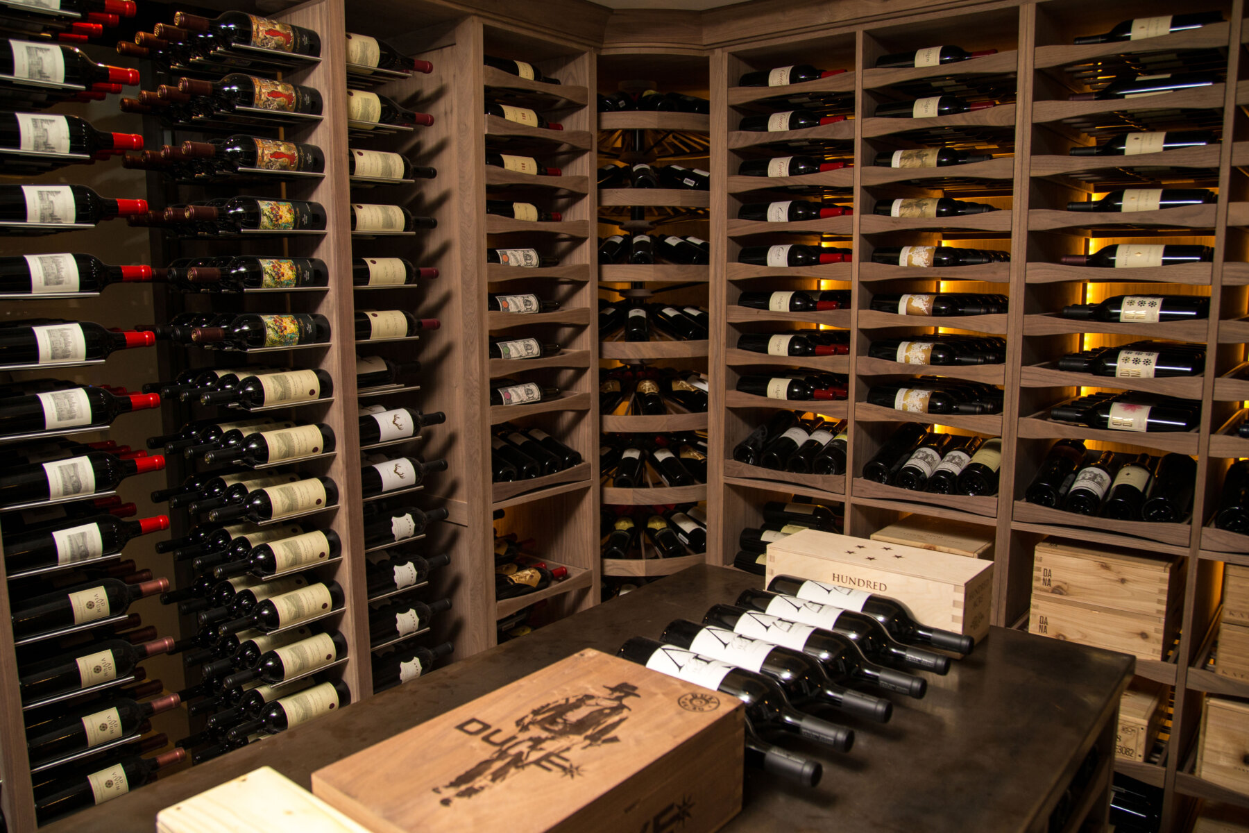 Custom walnut wine cellar with pullout wine drawers, rotating wine storage towers, and center island.