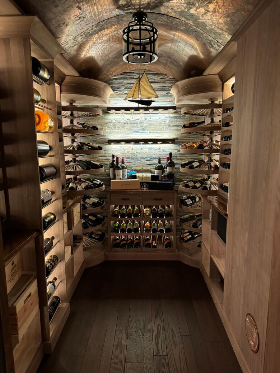 Custom rustic wine cellar with stone backsplash and label-forward cabinetry